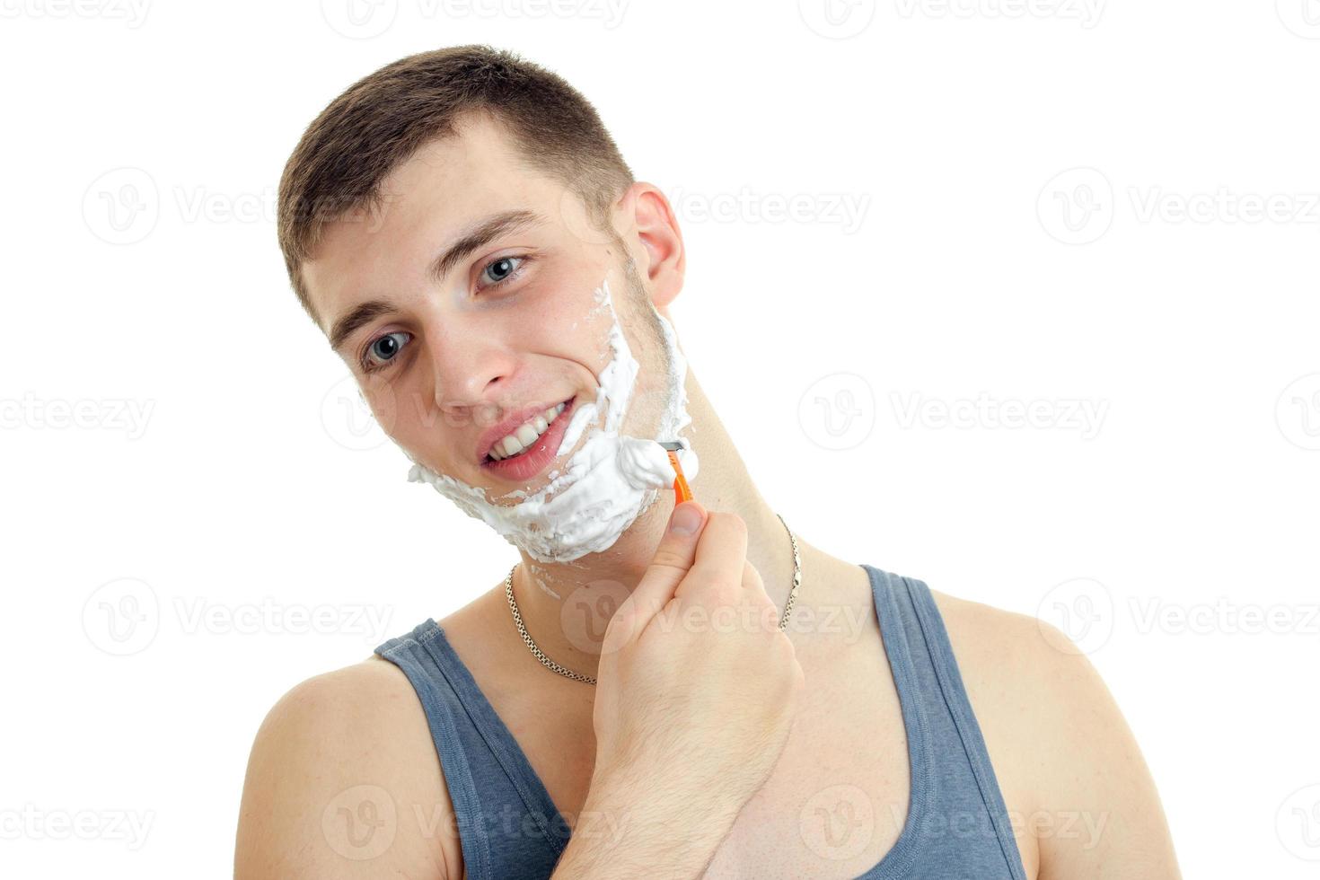 detailopname portret van een jong schattig vent met schuim Aan zijn gezicht wie scheert zijn baard en glimlachen foto