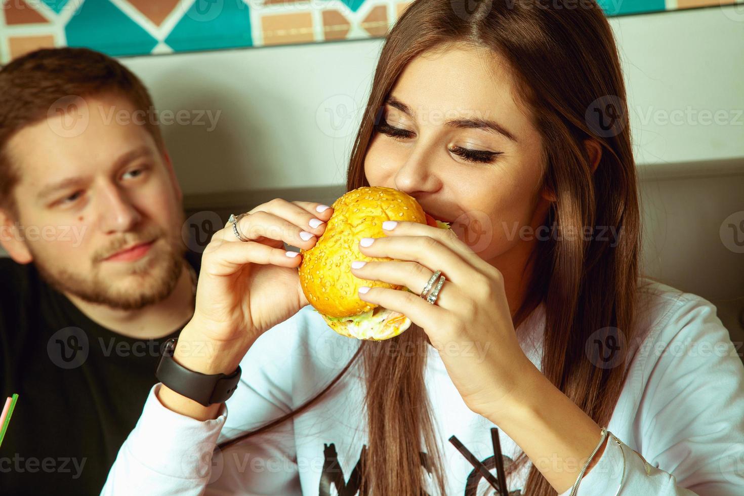 vrouw eet Hamburger Bij de cafe foto