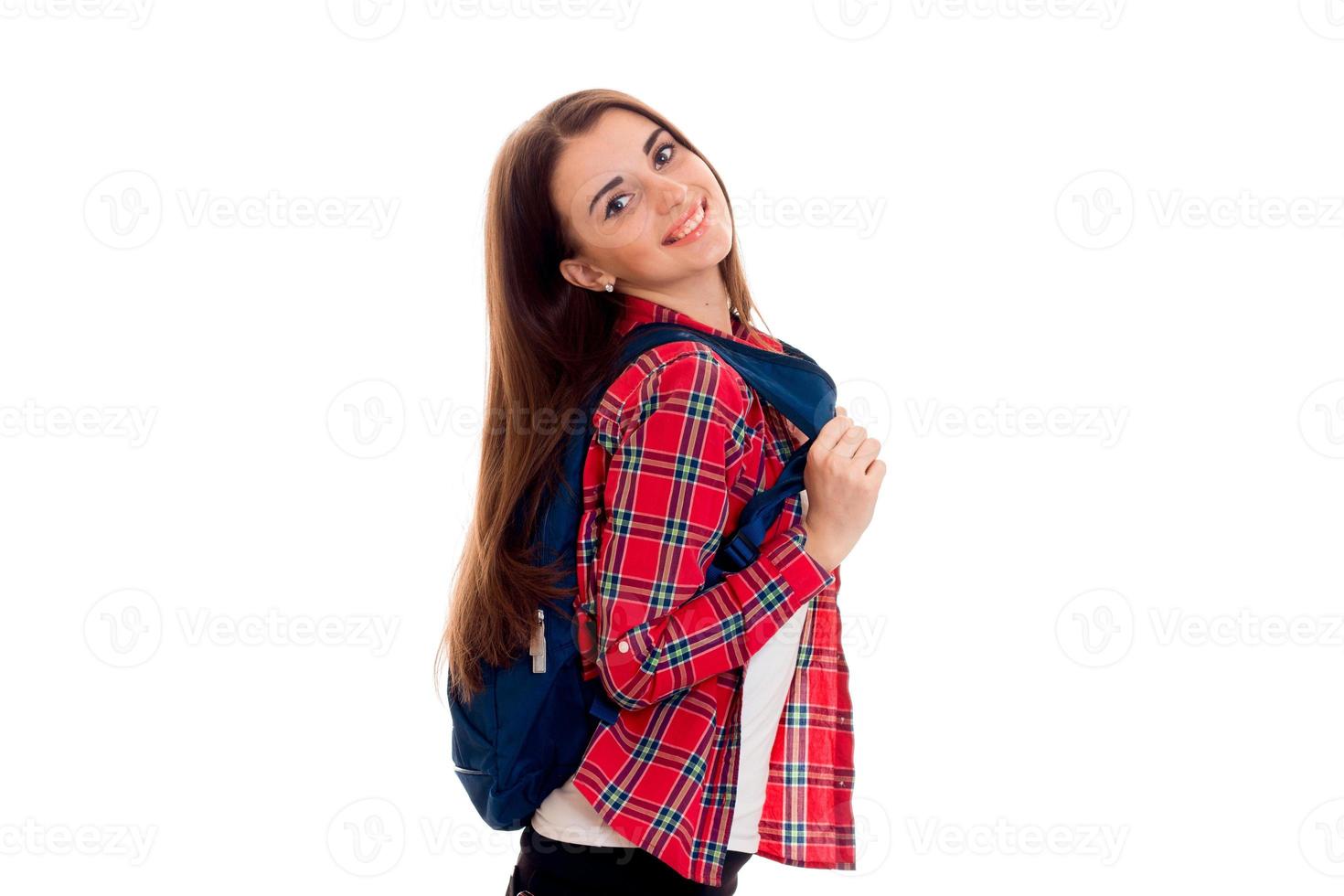 vrolijk elegant slim leerling meisje met rugzak Aan haar schouders poseren en glimlachen Aan camera geïsoleerd Aan wit achtergrond foto