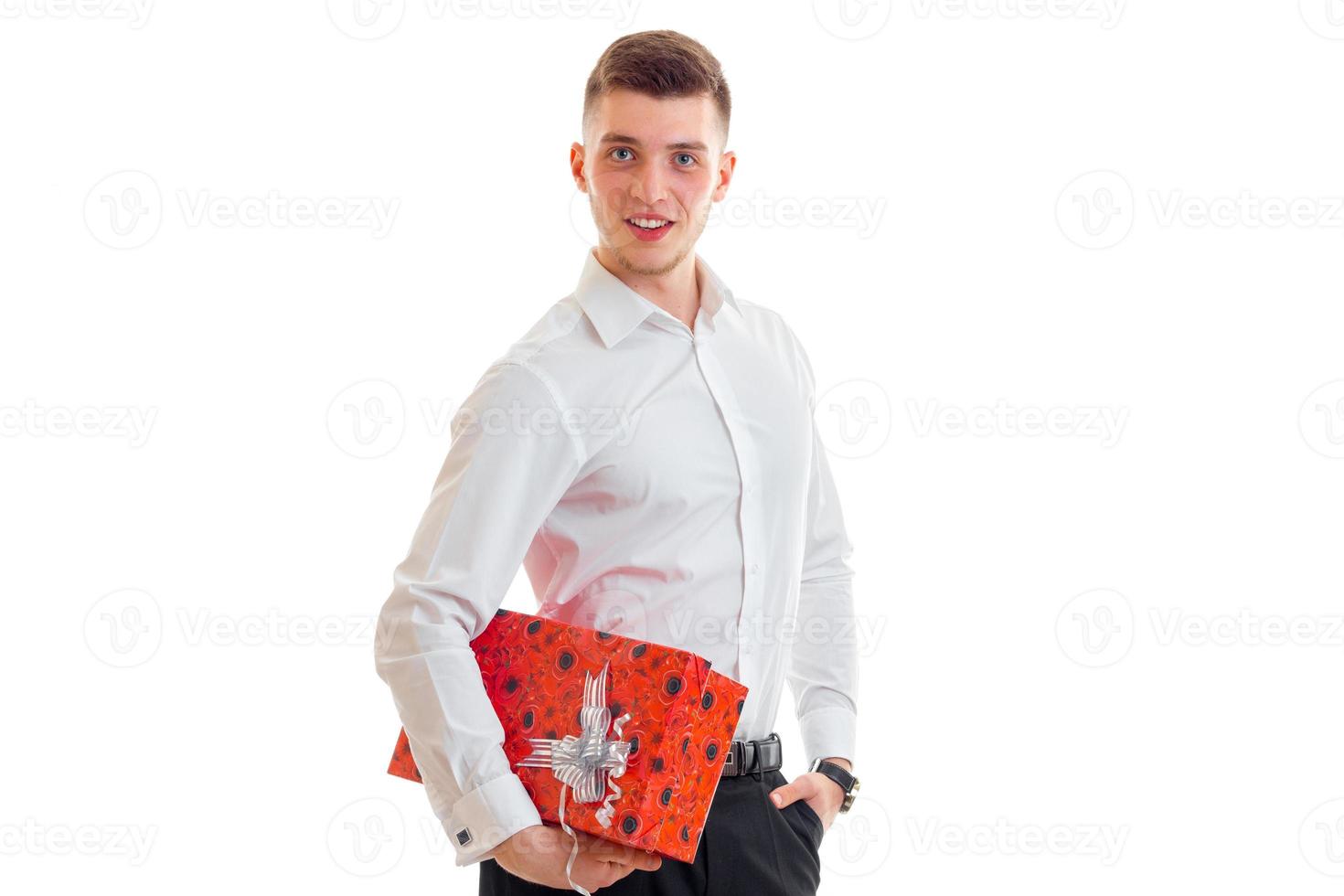 jong Mens in een wit overhemd met een groot rood geschenk glimlacht Bij de camera foto