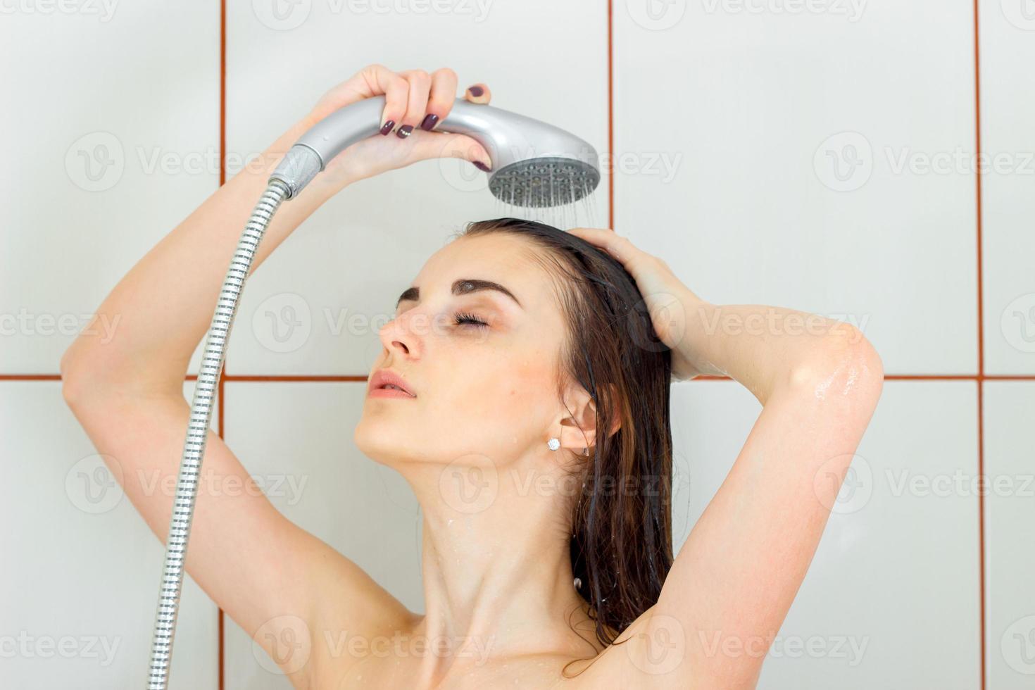 mooi jong brunette wast haar haar- in de douche foto