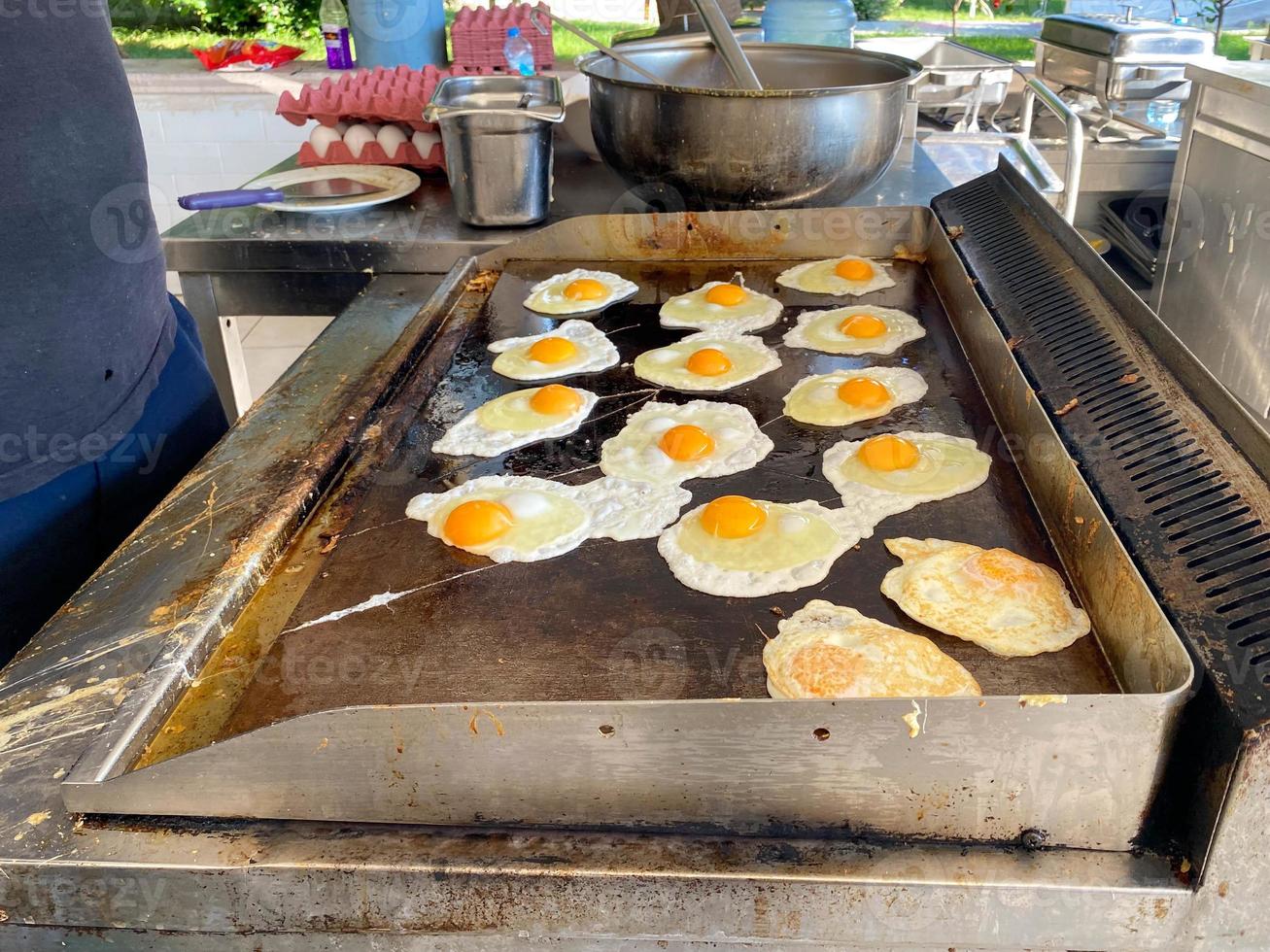 chef, koken kookt een veel van eieren Aan de fornuis, door elkaar gegooid eieren in een restaurant in een Open keuken in een all-inclusive hotel in een toerist warm tropisch land paradijs toevlucht Aan vakantie foto