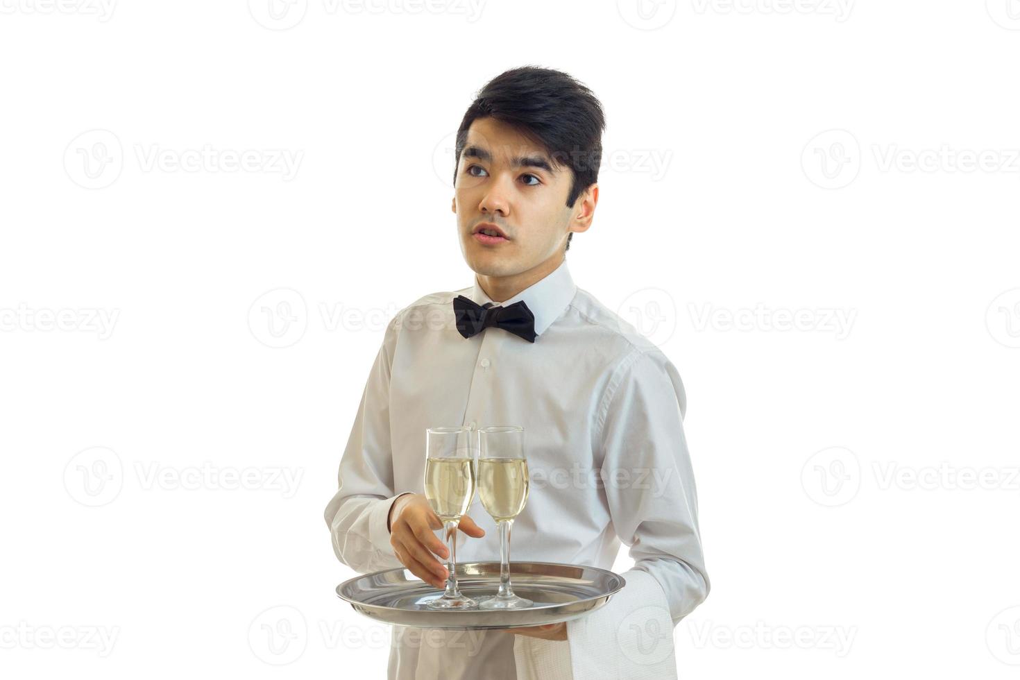 de jong ober looks weg en duurt de bal dienblad met een glas van Champagne foto