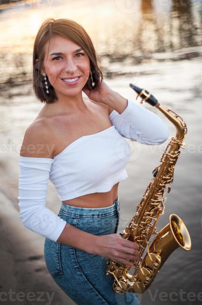 vrouw die saxofoon speelt bij zonsondergang foto
