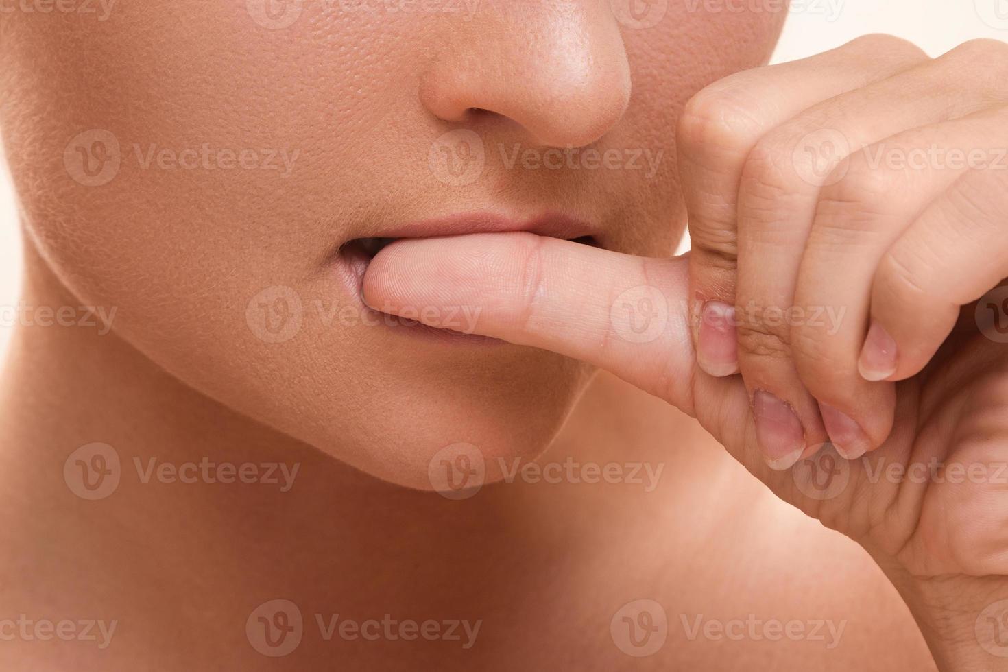 detailopname van een vrouw mond bijten haar vingers foto