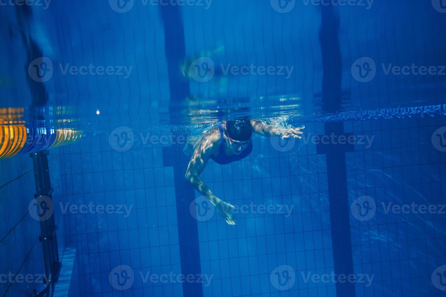 zwemmer vrouw onderwater- gedurende haar training in de zwembad foto
