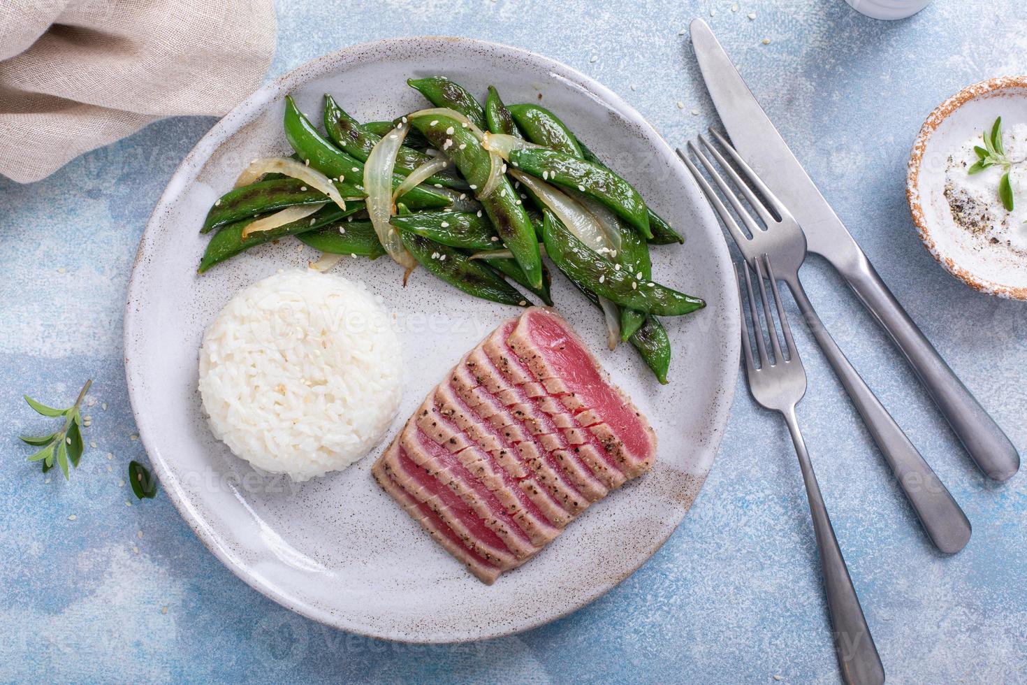 aangebraden tonijn steak met wit rijst- en groen erwten foto