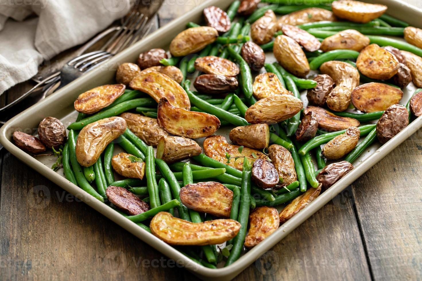 geroosterd krokant vingeren aardappelen met groen bonen Aan een vel pan foto