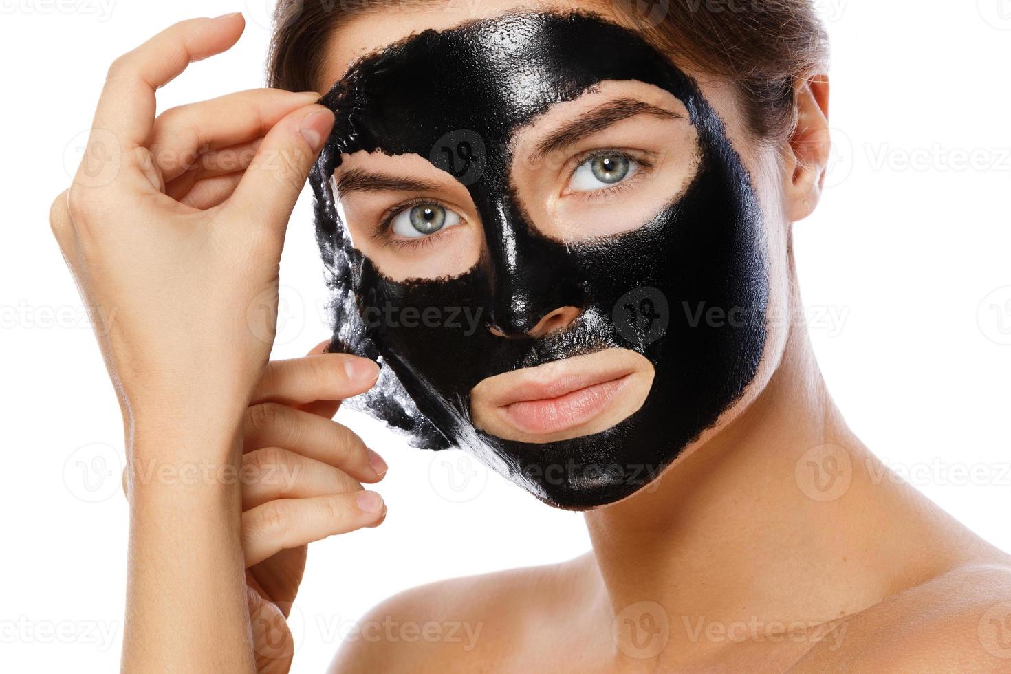 mooi vrouw is Verwijderen zuiverend masker van haar gezicht foto