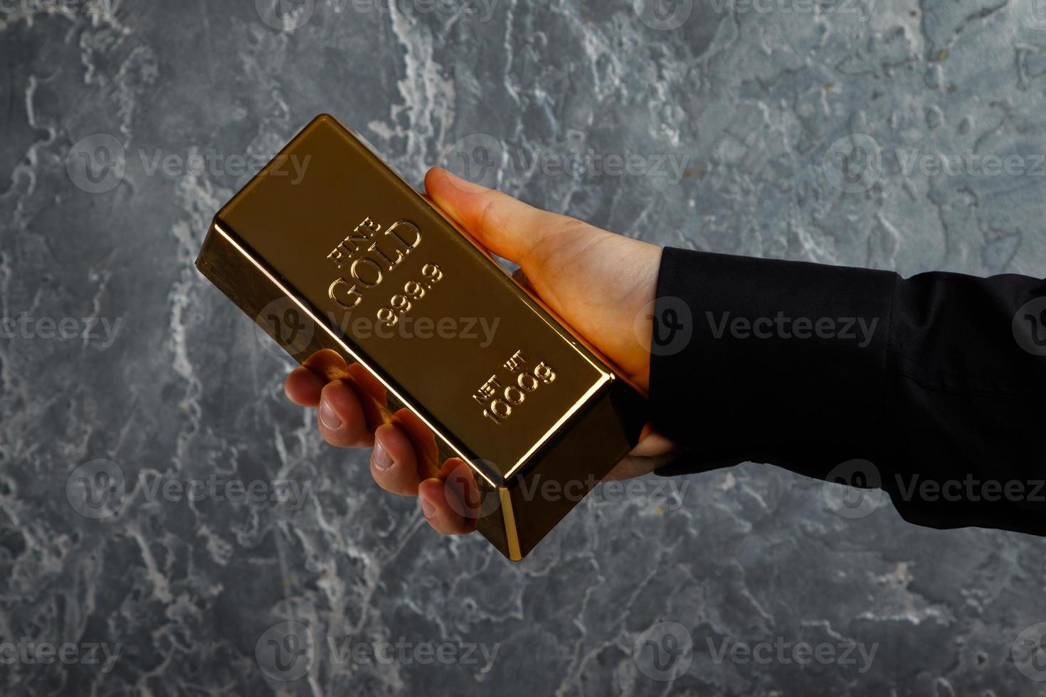 mannetje hand- met een goud bar tegen getextureerde muur foto