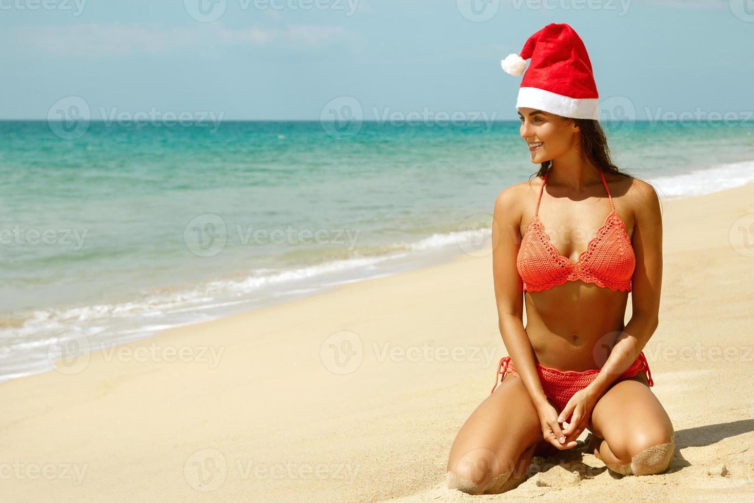 vrouw vervelend bikini en Kerstmis hoed Aan de strand. winter vakantie in de warm landen. foto