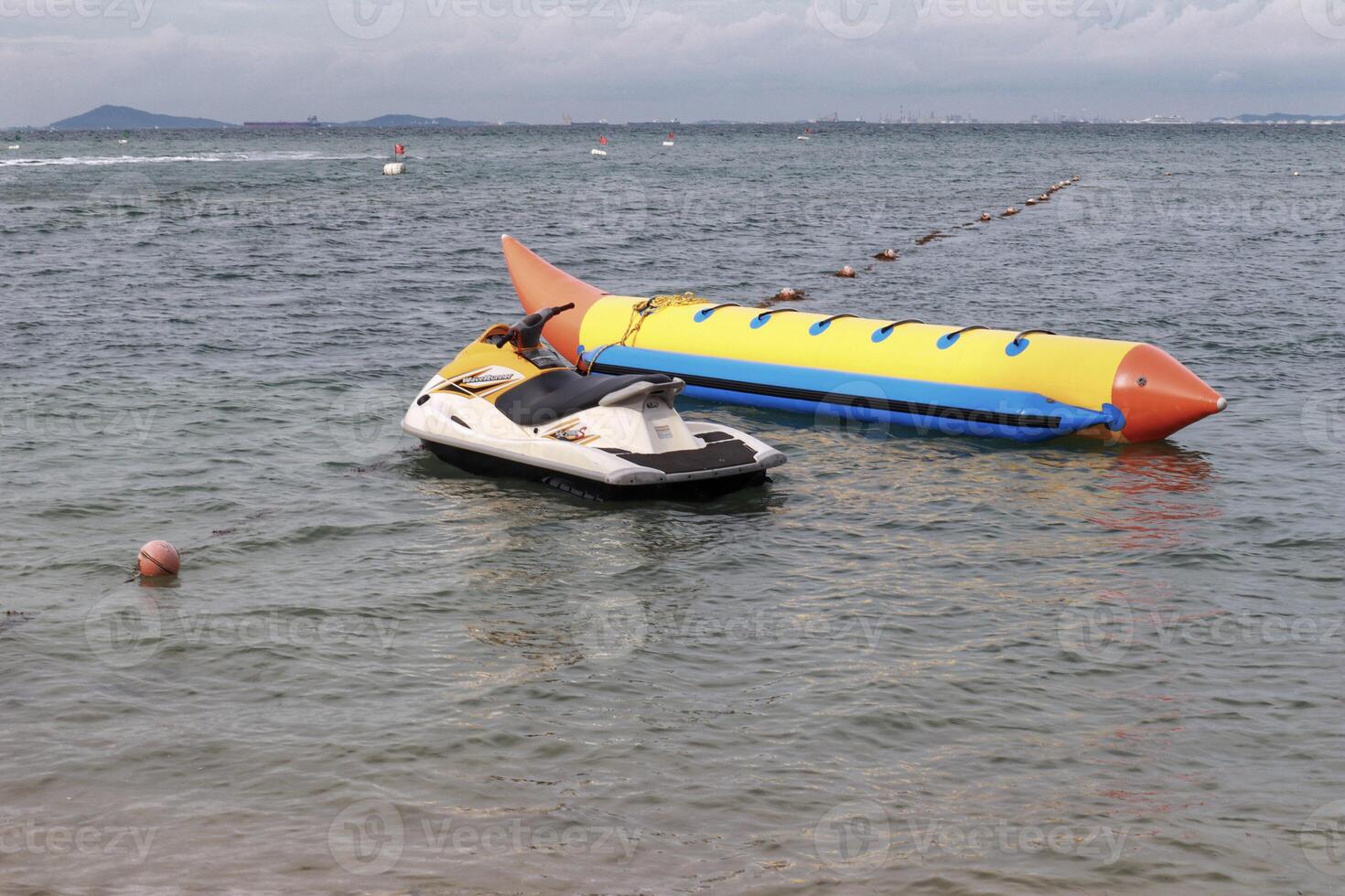 Jet ski en een geel banaan boot voor familie attractie Bij strand. foto