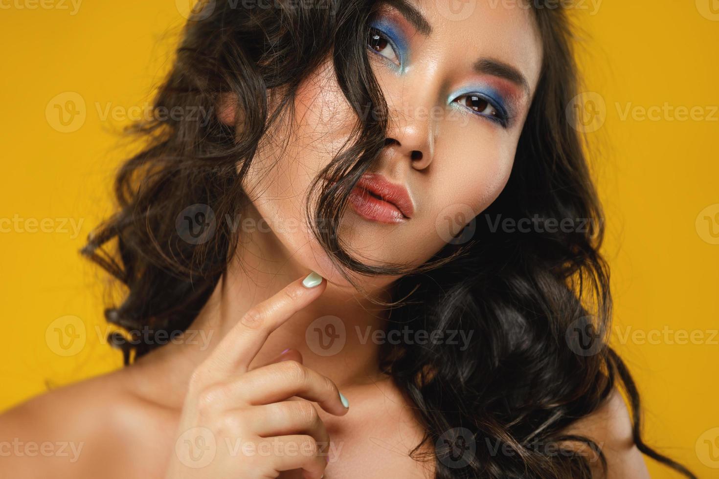 Aziatisch vrouw met een mooi gekruld haar- en bedenken Aan geel achtergrond foto