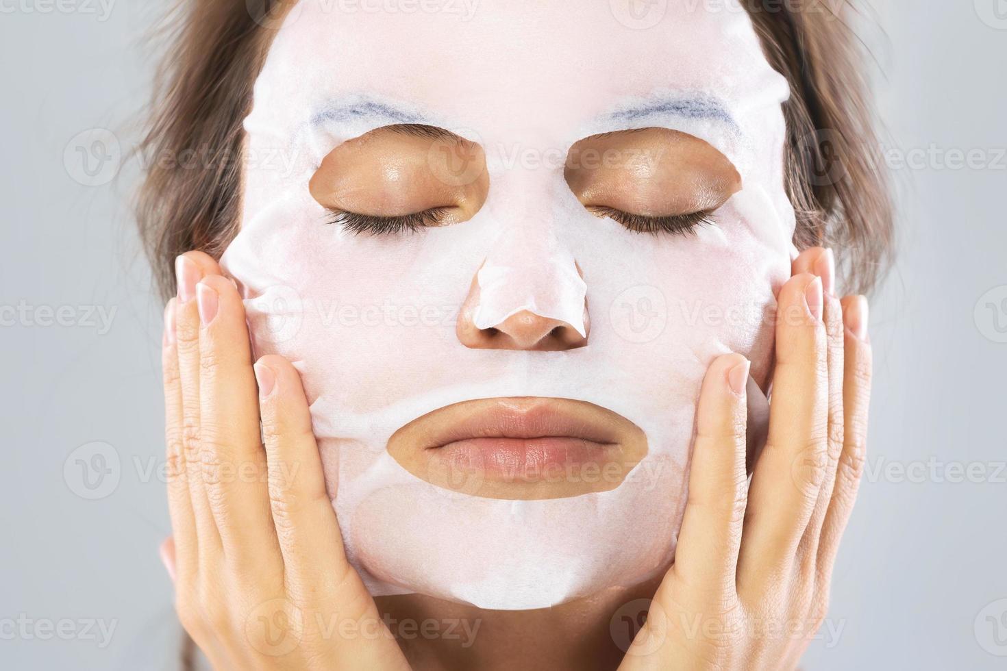 vrouw met een vel hydraterend masker Aan haar gezicht geïsoleerd Aan grijs achtergrond foto