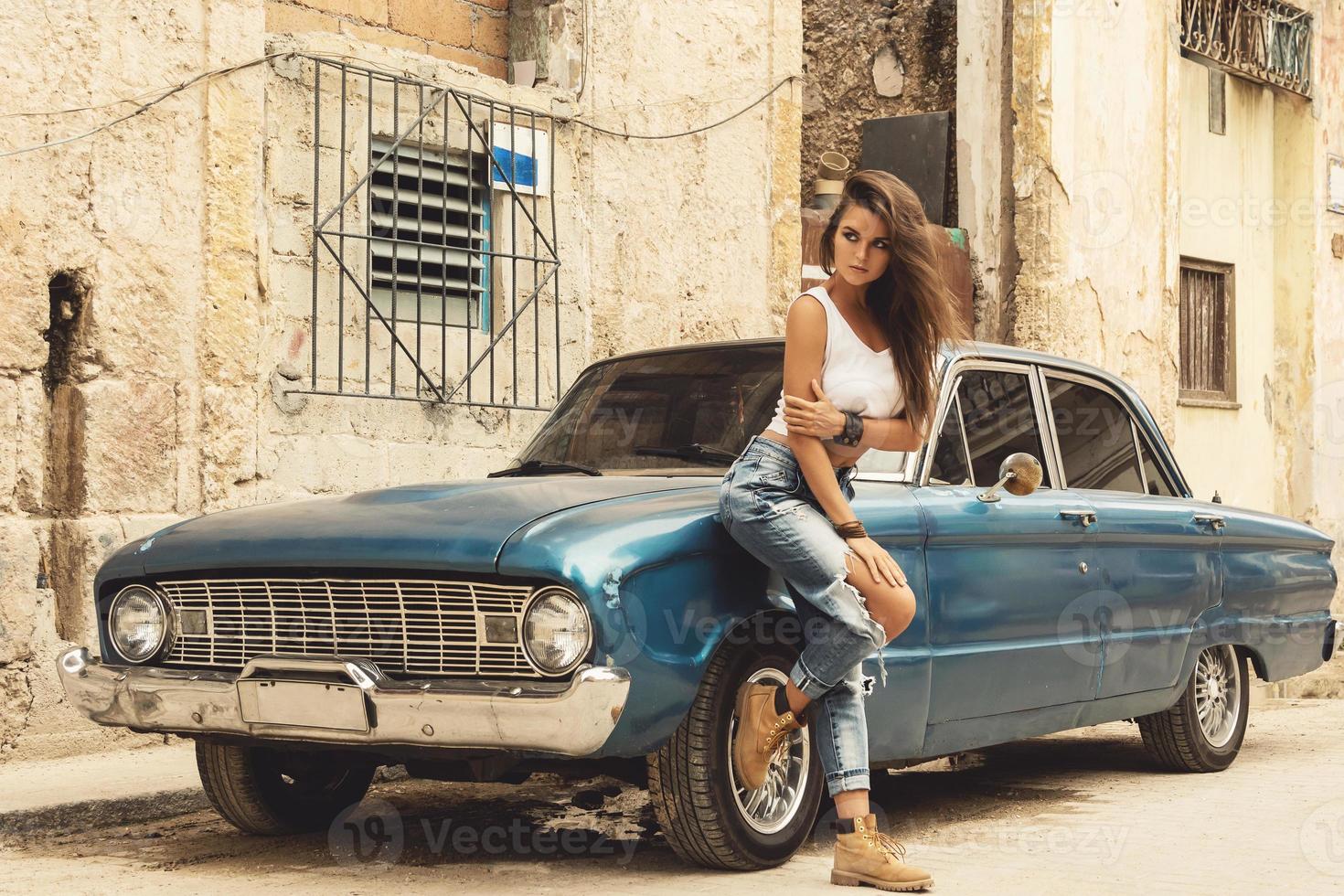 vrouw is poseren naast oud auto Aan de straat foto