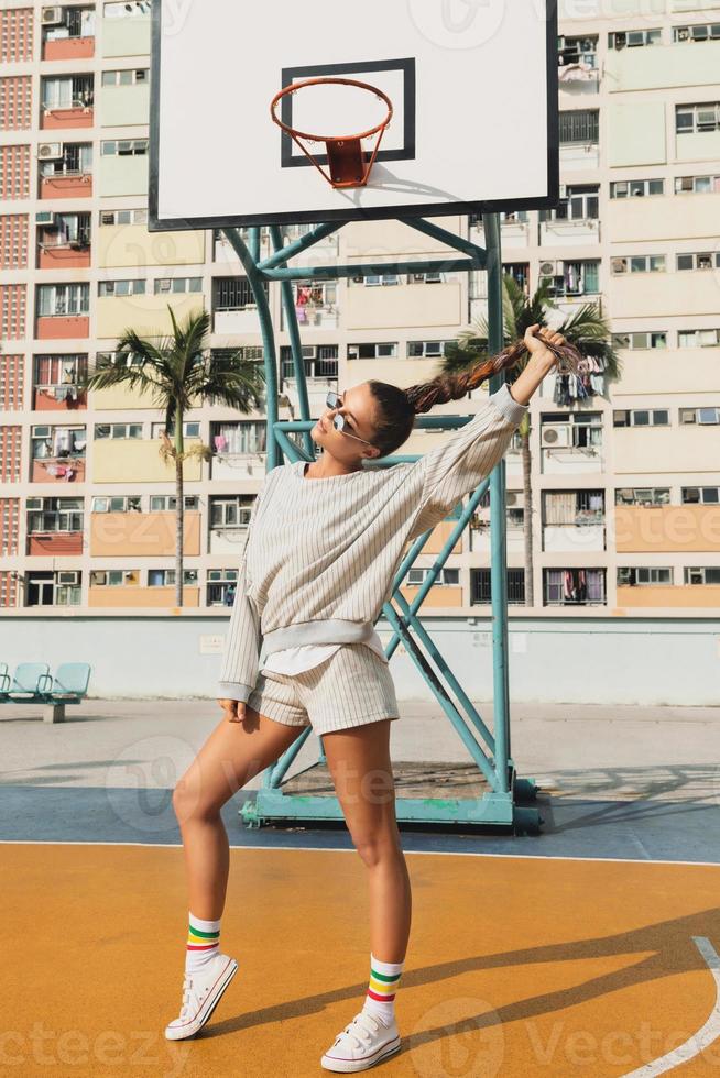 jong elegant vrouw is poseren Aan de choi hing landgoed basketbal rechtbank foto