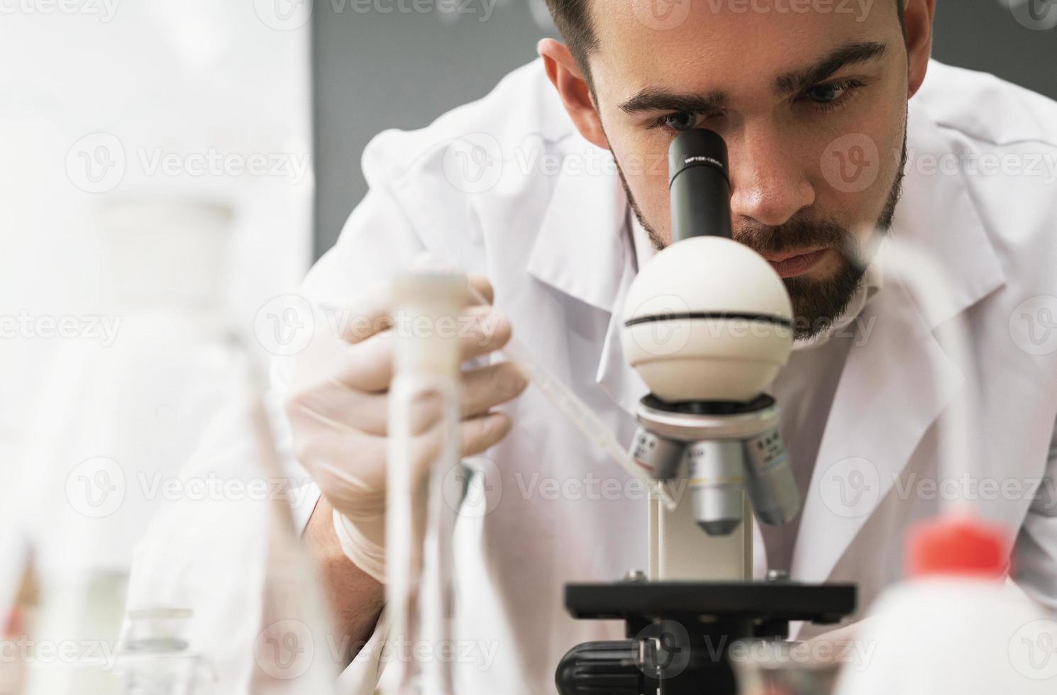 wetenschapper is gebruik makend van microscoop in een laboratorium gedurende Onderzoek foto