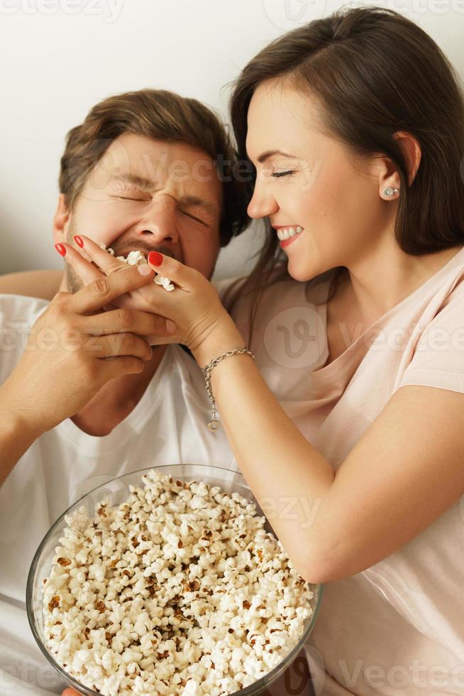 gelukkig paar aan het eten popcorn en aan het kijken film Bij huis foto