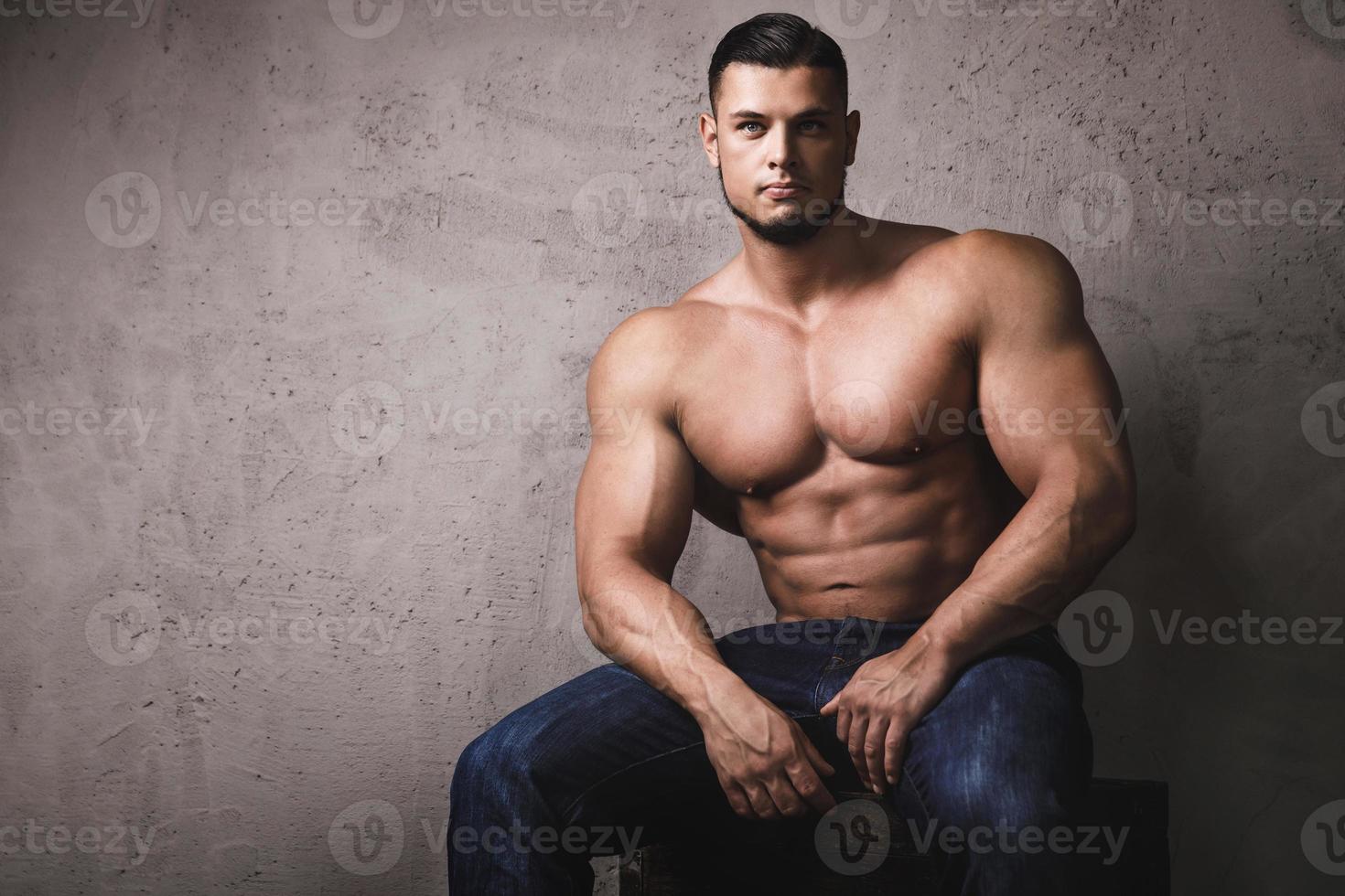 enorm bodybuilder poseren naast de beton muur foto