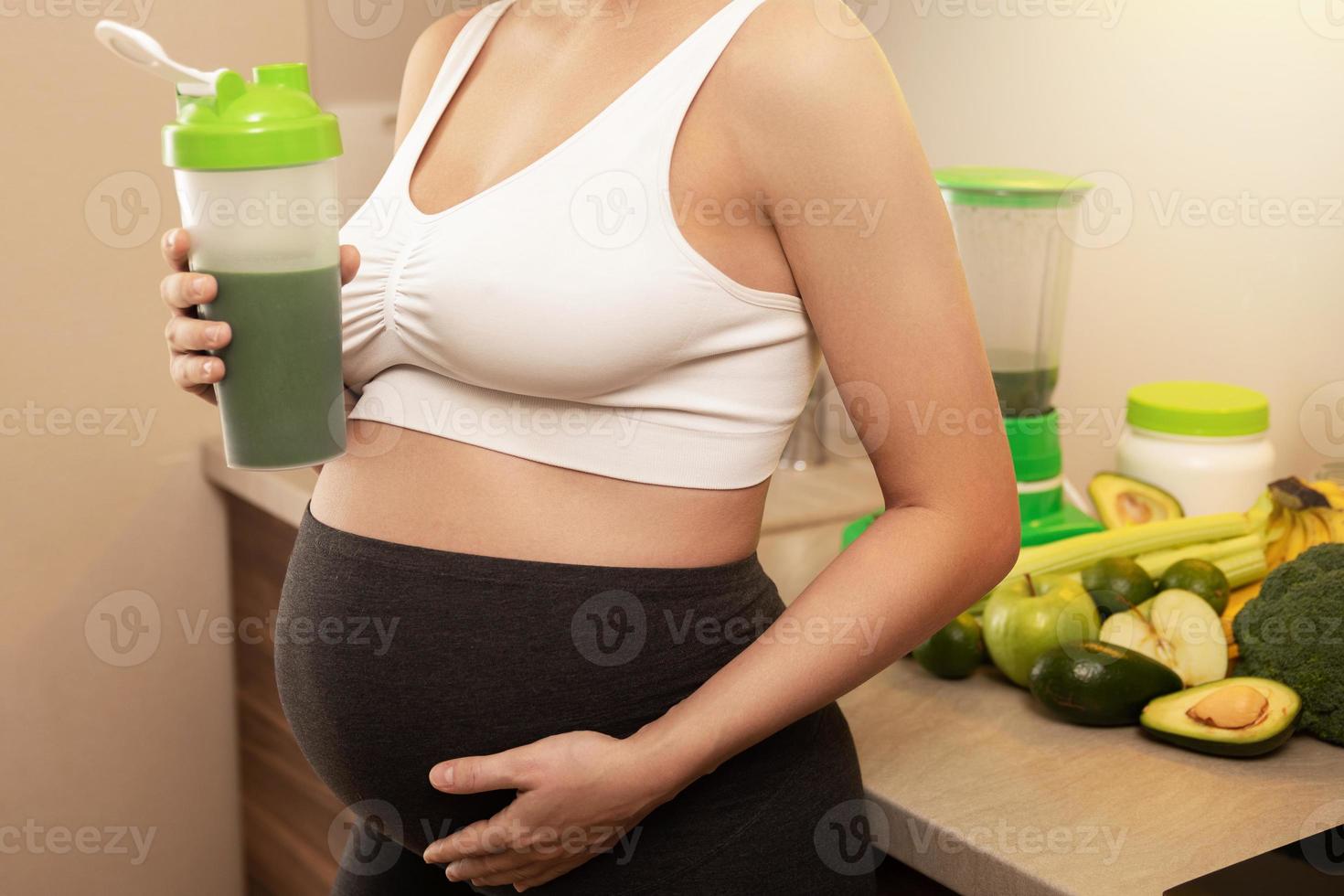 zwanger vrouw Holding shaker met een groen eiwit cocktail foto