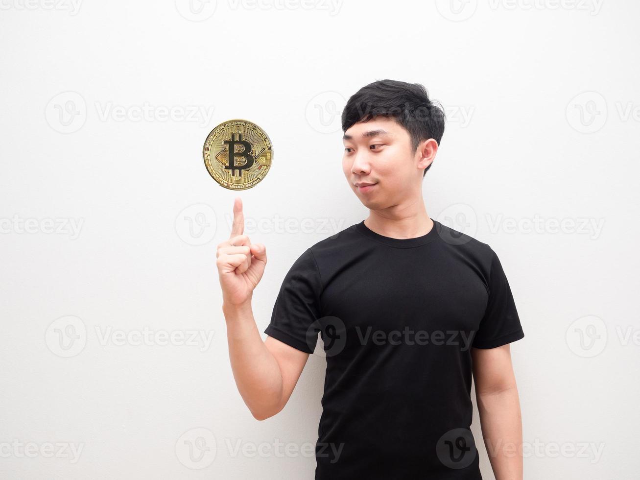 Aziatisch Mens kijken Bij goud bitcoin Aan zijn vinger omhoog Rechtsaf hand- Aan wit geïsoleerd achtergrond crypto geld concept foto
