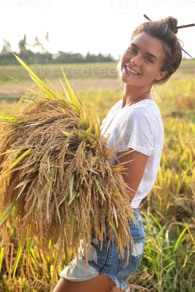 gelukkig vrouw boer gedurende oogsten Aan de rijst- veld- foto