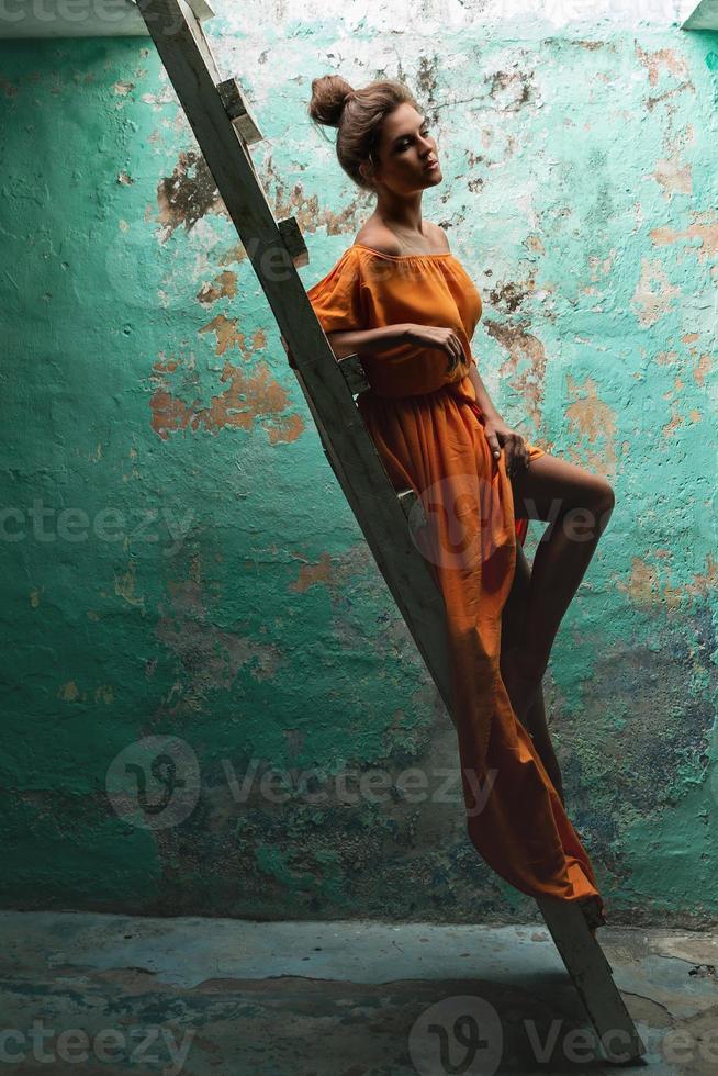 sensueel vrouw vervelend mooi lang jurk Aan de oud houten ladder foto