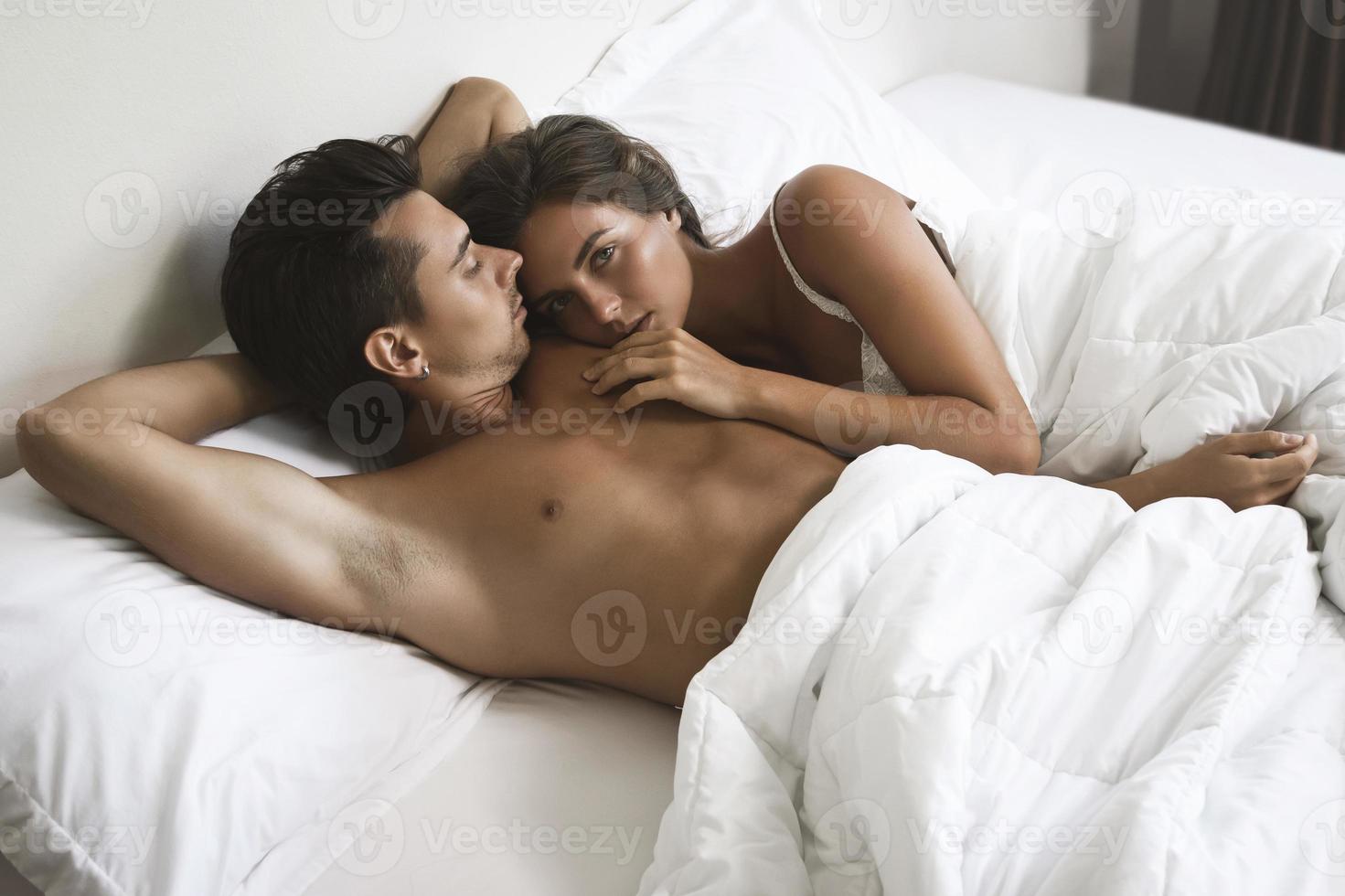 jong mooi paar is aan het liegen in de bed Bij ochtend- foto