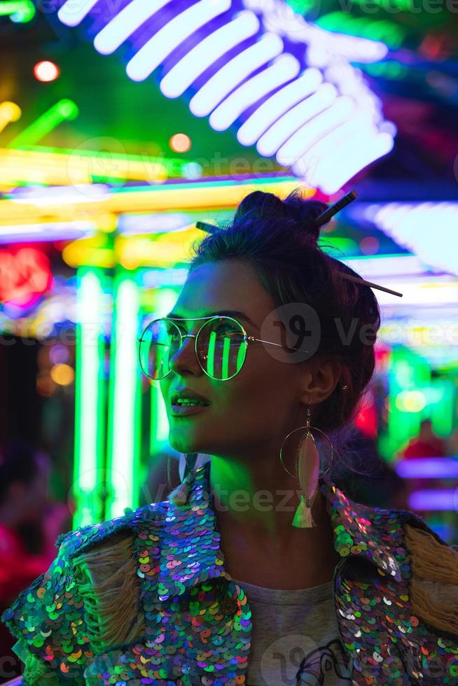 elegant vrouw vervelend jasje met schijnend pailletten Aan de stad straat met neon lichten foto