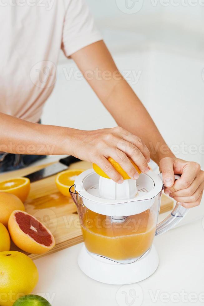 vrouw handen en citrus sapcentrifuge gedurende vers oranje sap voorbereiding foto