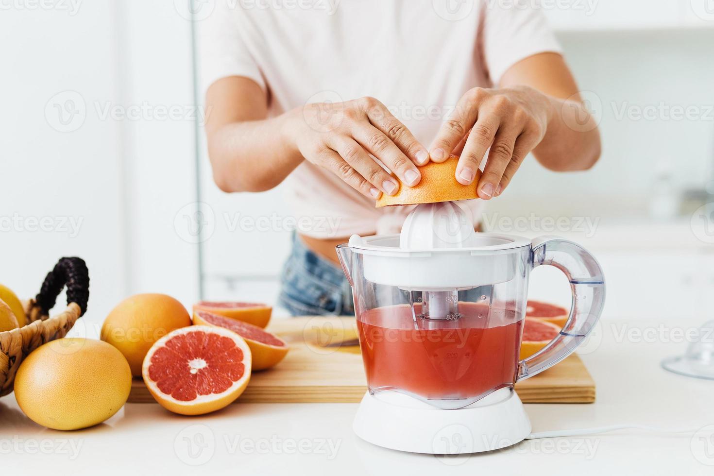 vrouw handen en citrus sapcentrifuge gedurende vers grapefruit sap voorbereiding foto