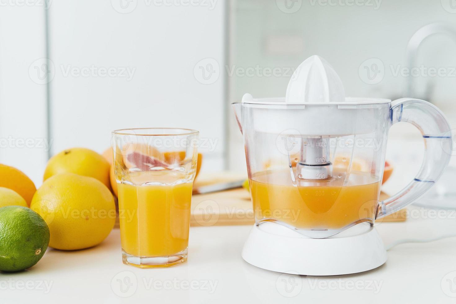 glas van oranje sap, citrus sapcentrifuge en divers citrus fruit Aan keuken tafel foto