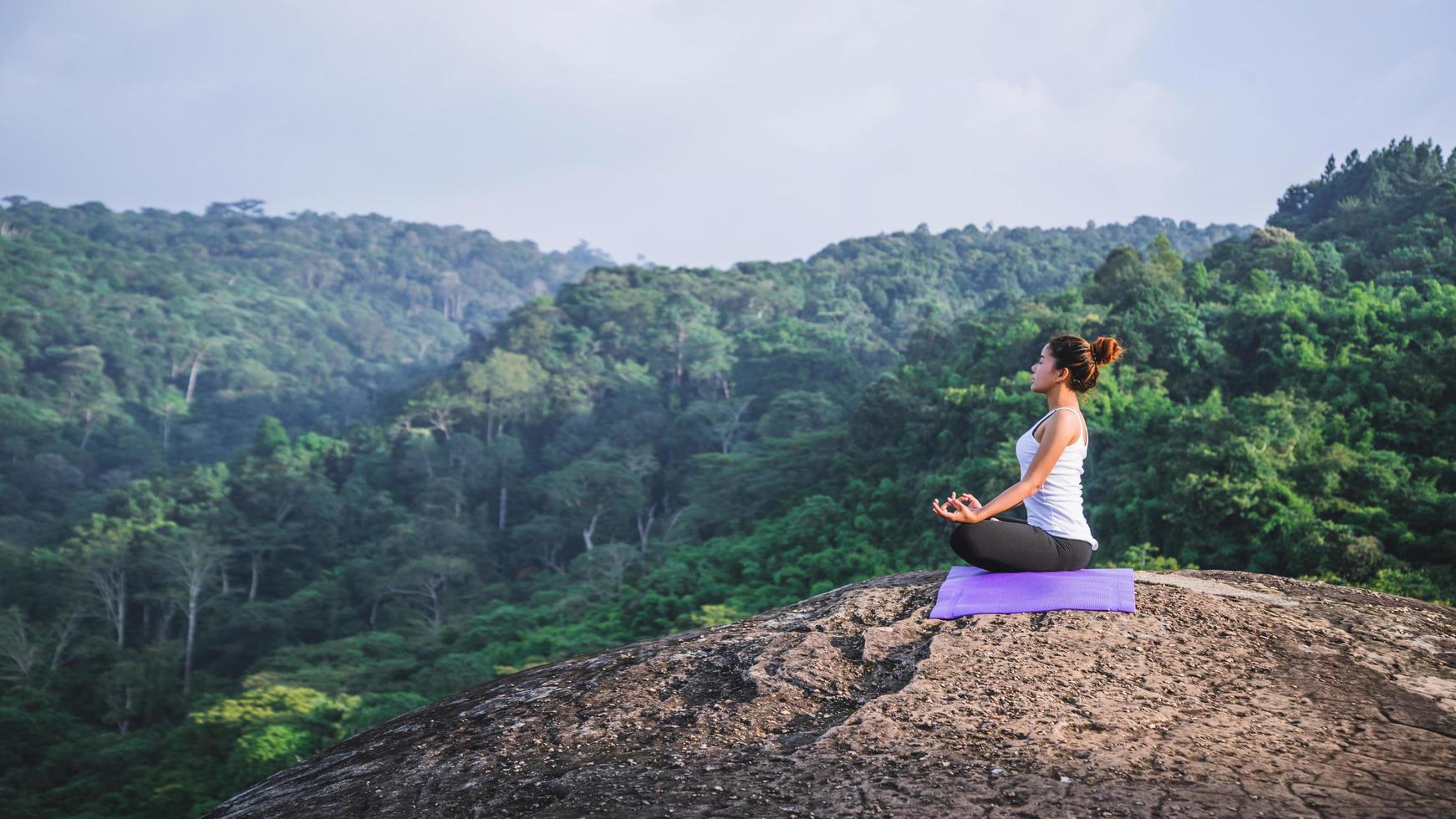 Aziatische vrouwen ontspannen in de vakantie. spelen als yoga. op de berg rots klif. aard van bergbossen in thailand. jonge vrouw die yoga beoefent in de natuur vrouwelijk geluk. yoga beoefenen foto