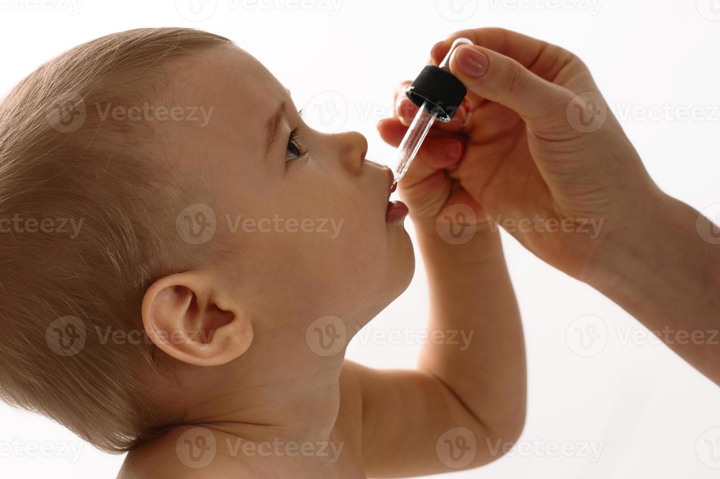 moeder geeft vitamine d naar haar weinig zoon. foto