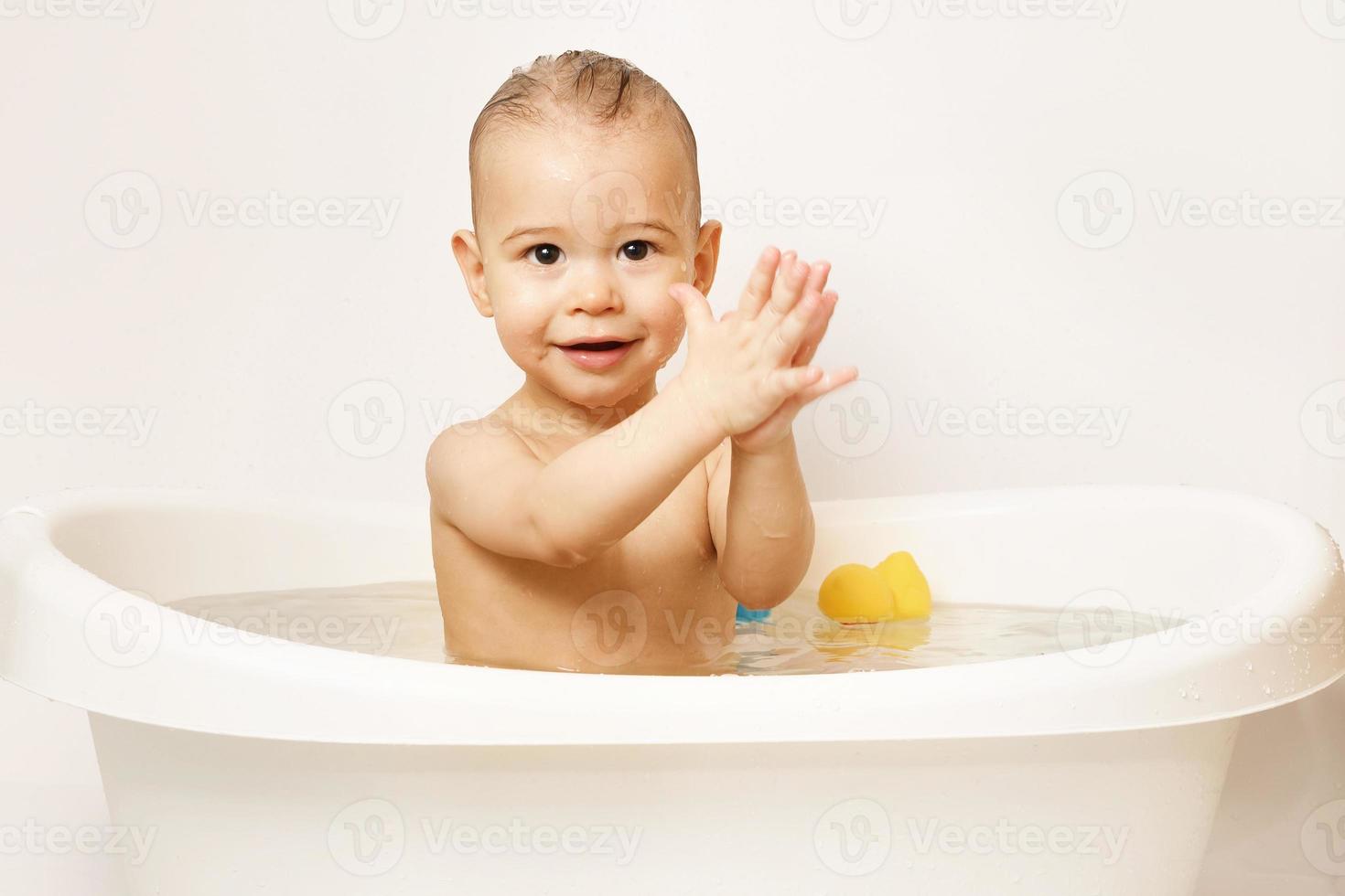 glimlachen weinig jongen nemen een bad met rubber speelgoed. foto