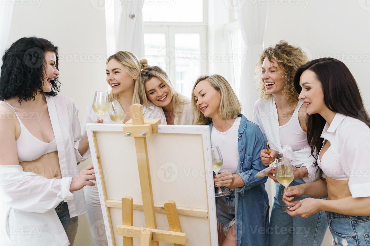 groep van Dames verf Aan canvas en drinken wit wijn gedurende partij Bij huis foto