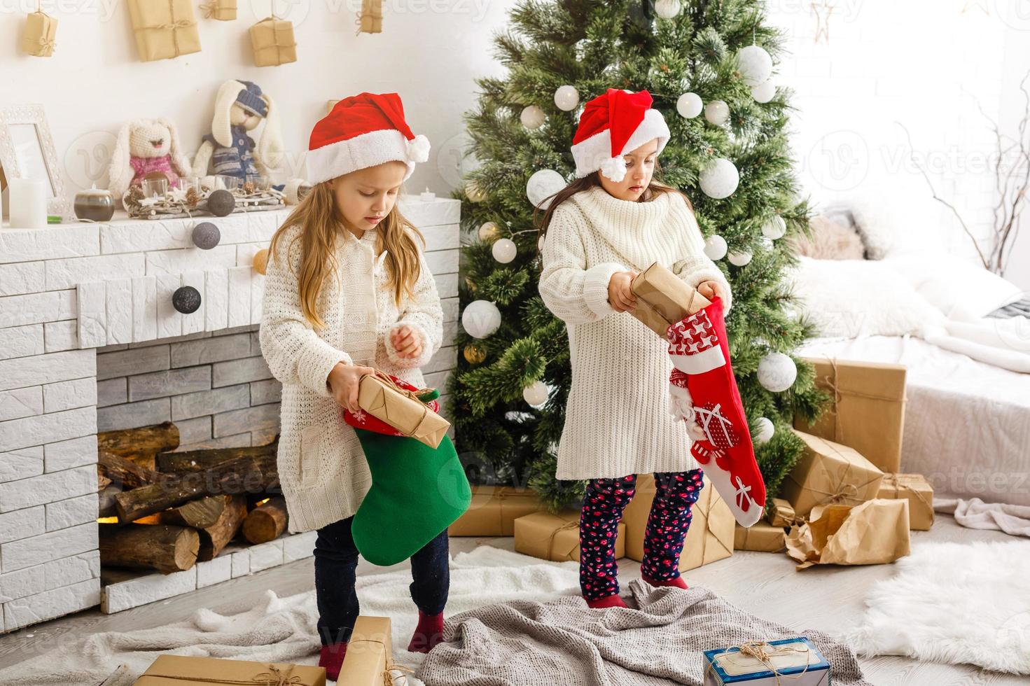 kinderen weinig zussen houden cadeaus dozen interieur achtergrond. wat een Super goed verrassing. klein schattig meisjes ontvangen vakantie geschenken. het beste speelgoed en Kerstmis geschenken. kinderen vrienden opgewonden uitpakken hun geschenken. foto