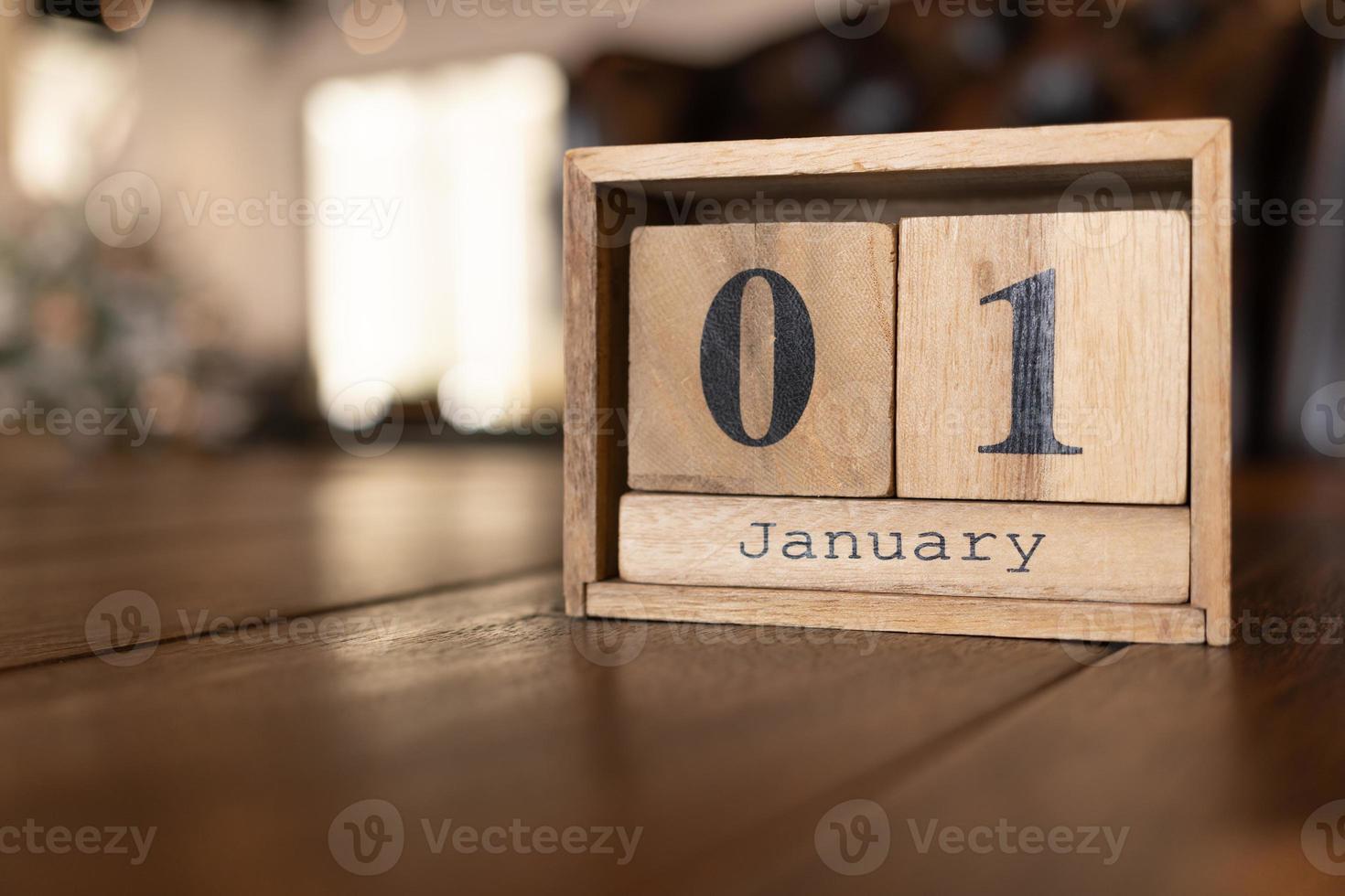 kubus vorm kalender voor januari 01 Aan houten oppervlak. houten bakstenen kalender met gegraveerde datum 01 januari staand Aan een bureau. foto