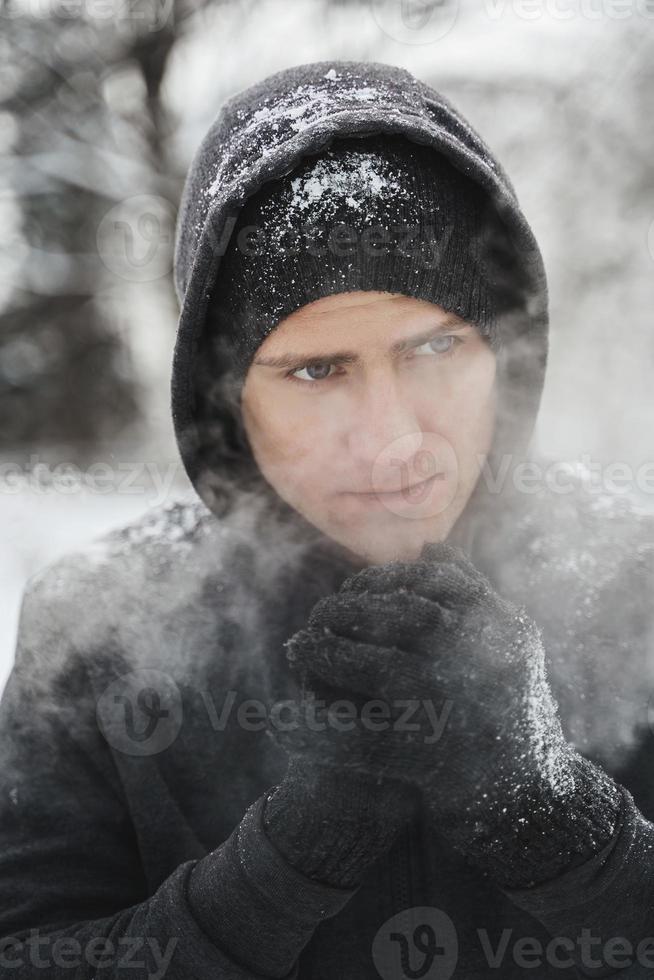 atletisch Mens vervelend capuchon gedurende zijn winter training in besneeuwd stad park foto