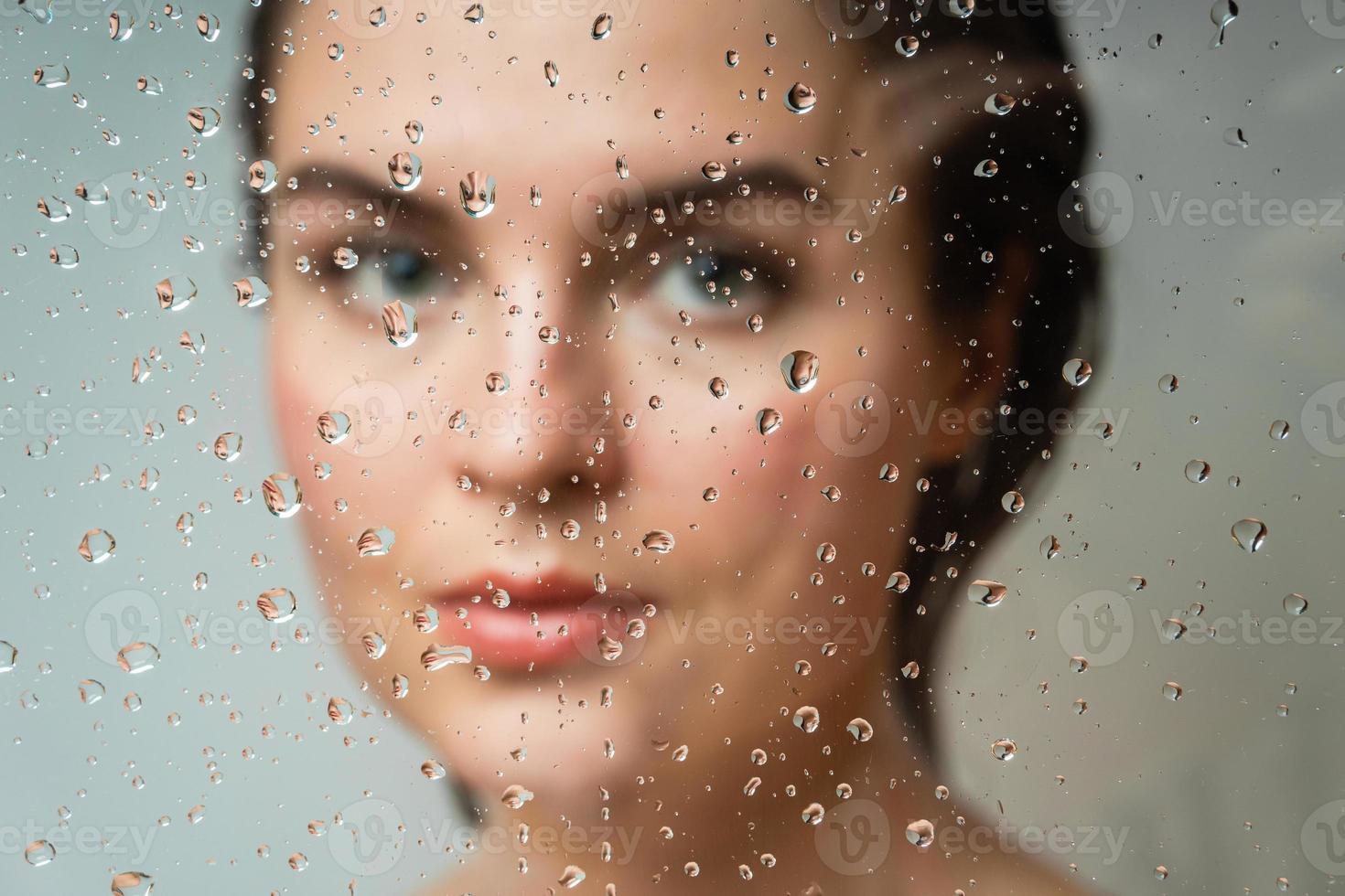 vrouw achter de nat glas. focus Aan de druppels. foto