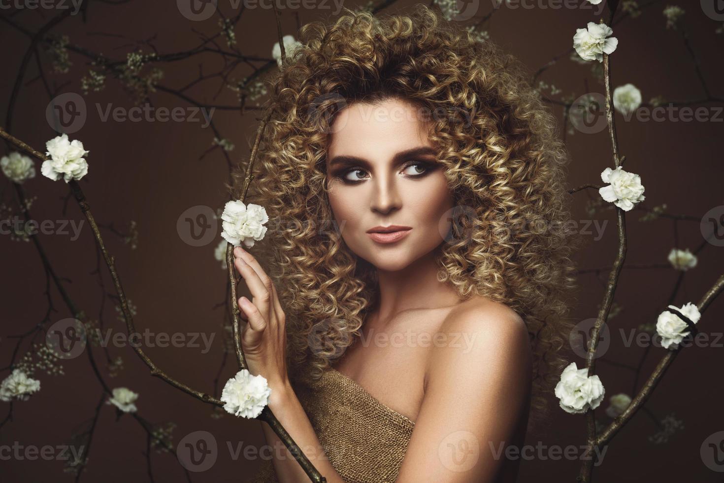 lief jong vrouw met afro kapsel en mooi bedenken met een veel van wit bloemen foto