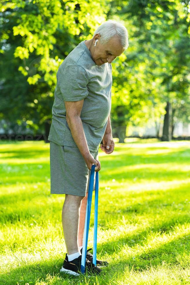 actief ouderen Mens oefenen met een rubber weerstand band in groen stad park foto