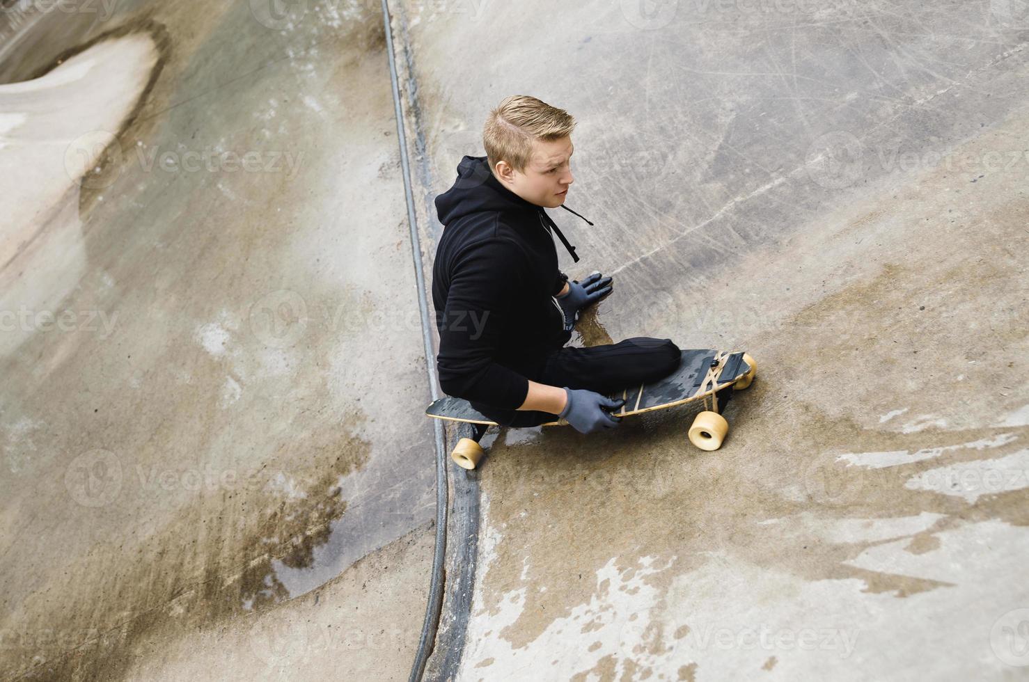 jong gehandicapten vent met een longboard in een skatepark foto
