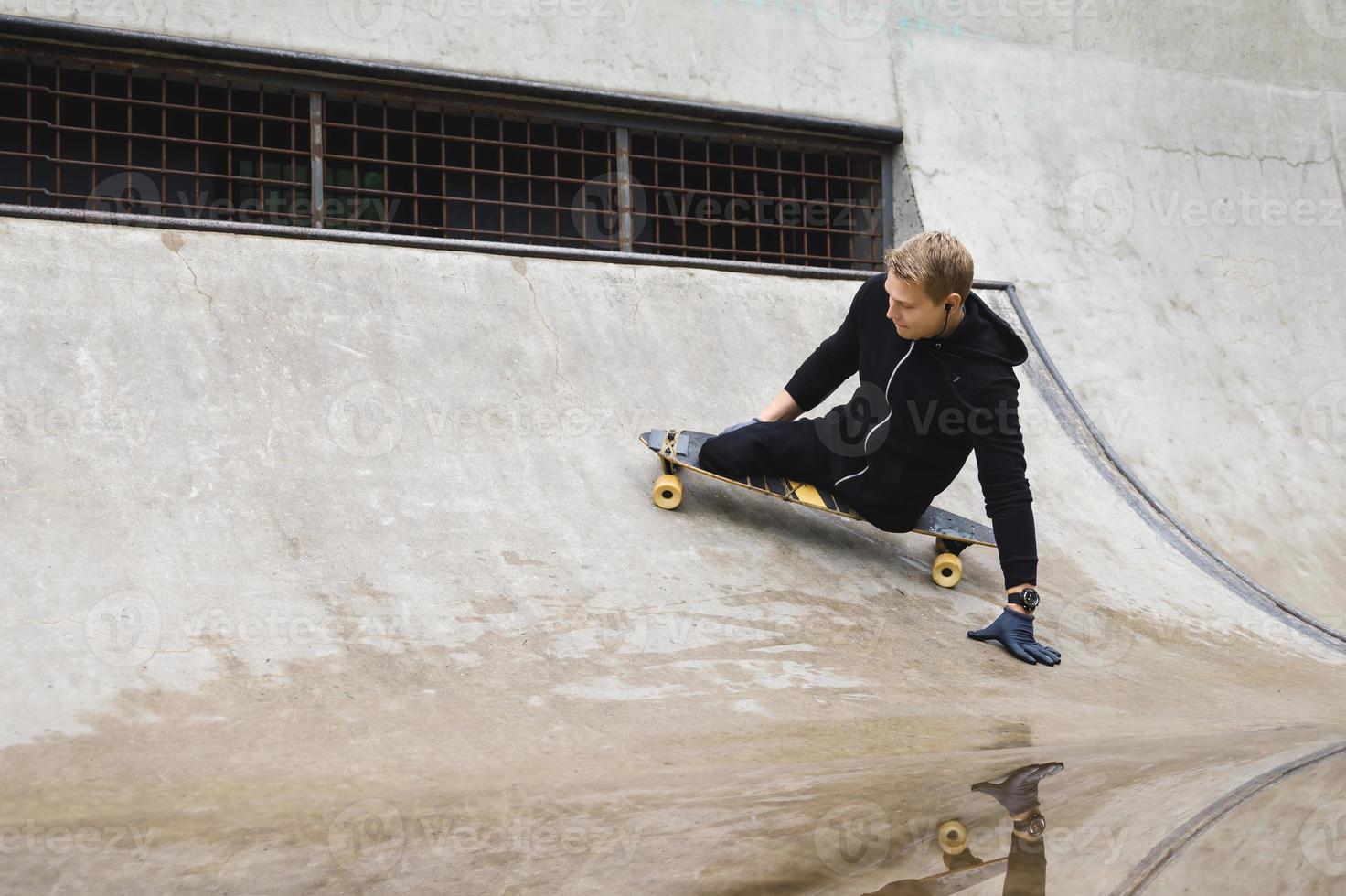 jong gehandicapten vent met een longboard in een skatepark foto