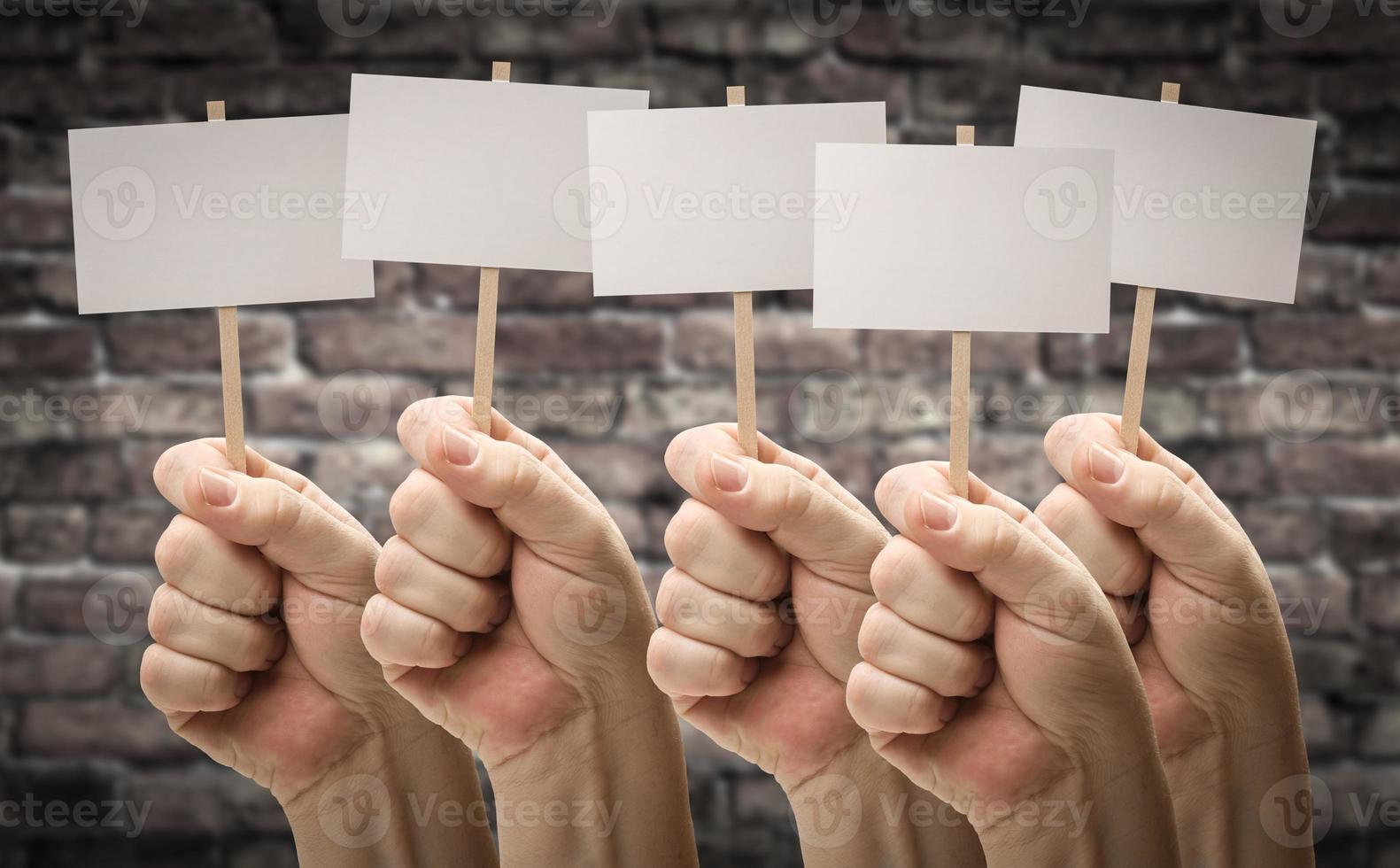 vijf mannetje handen Holding blanco tekens tegen oud steen muur foto