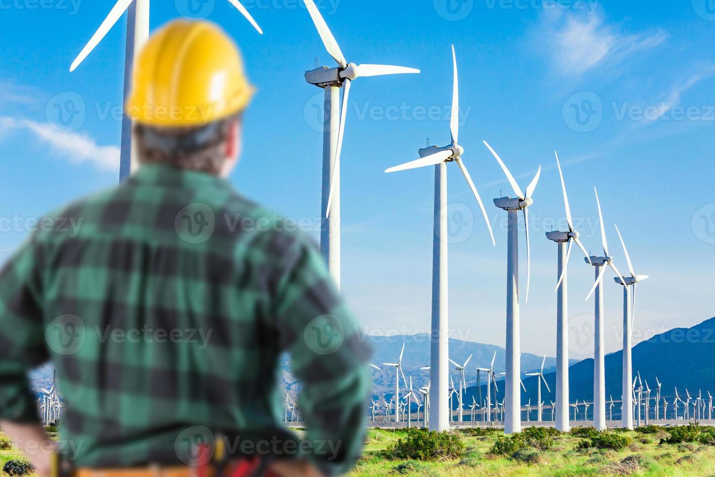 mannetje aannemer vervelend gereedschap riem en moeilijk hoed geconfronteerd alternatief energie wind turbines. foto