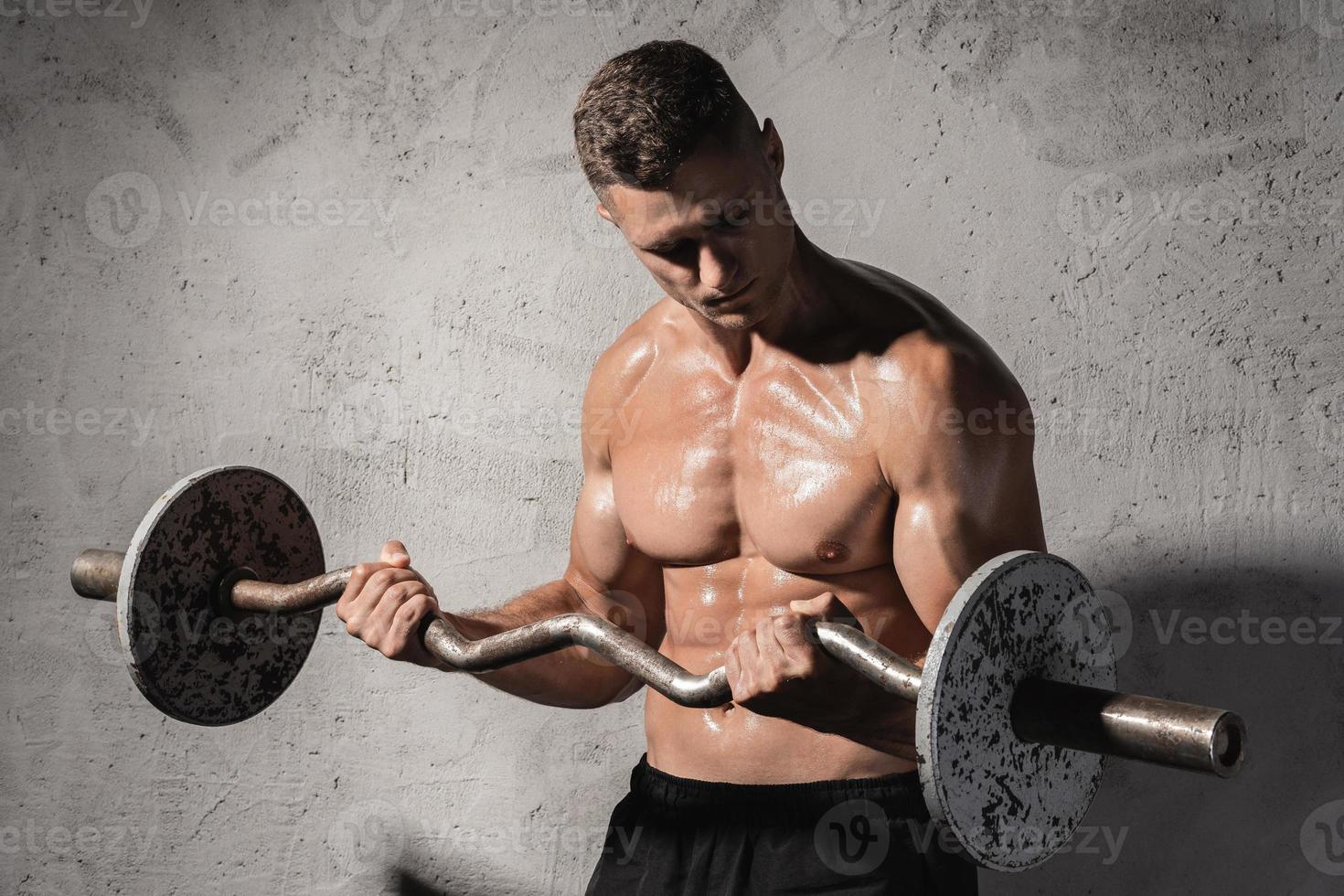 jong en gespierd bodybuilder werken uit met een barbell foto