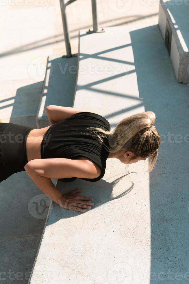 atletisch vrouw is aan het doen Opdrukken gedurende zomer gymnastiek training foto