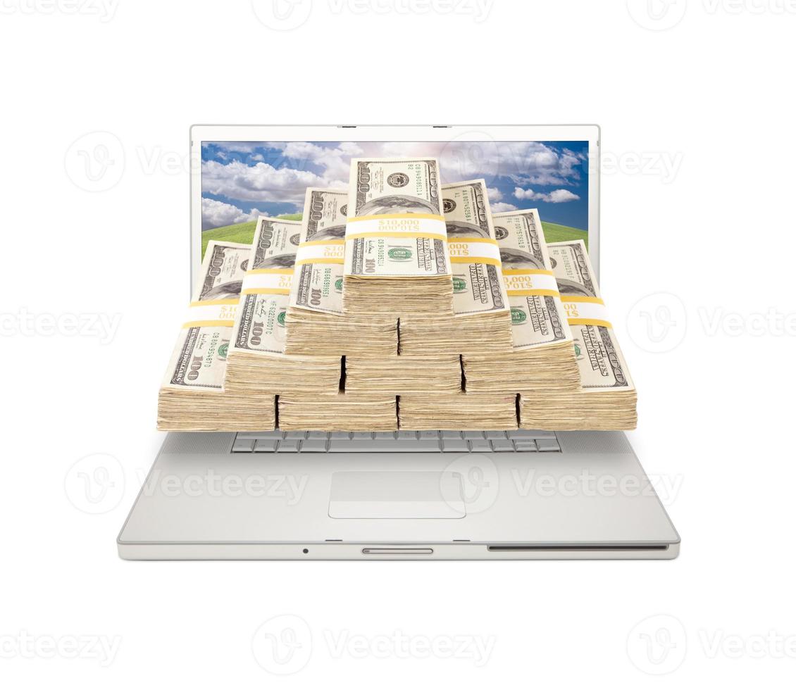 laptop met stapels van geld komt eraan van scherm foto