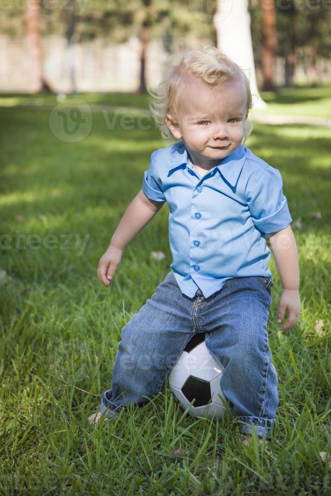 jong schattig jongen spelen met voetbal bal in park foto